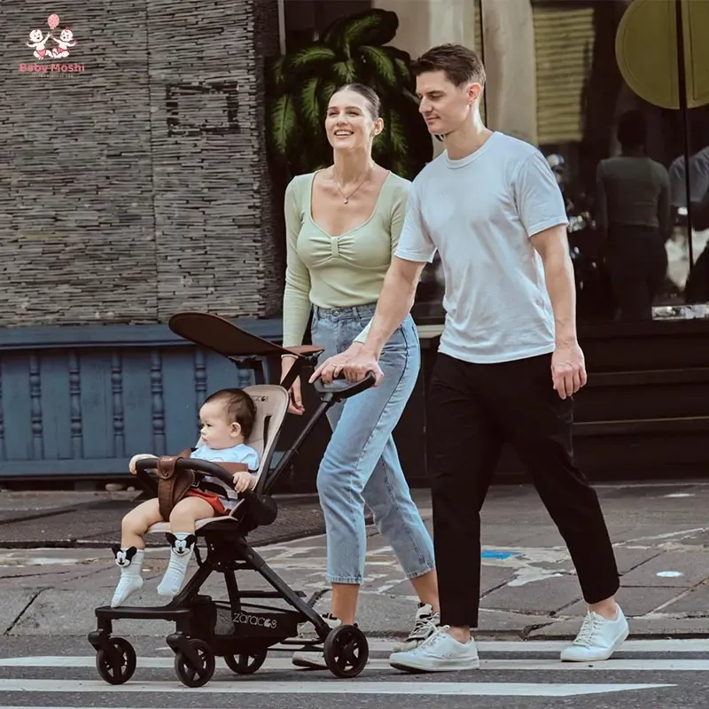 Ba mẹ đang mỉm cười đẩy em bé đi dạo trong một chiếc xe đẩy cao cấp, khung gầm chắc chắn