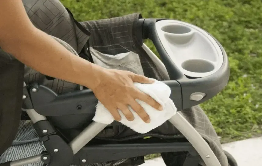 Ba mẹ đang dùng khăn ướt kháng khuẩn lau chùi nhanh khay ăn dặm của xe đẩy sau khi bé ăn