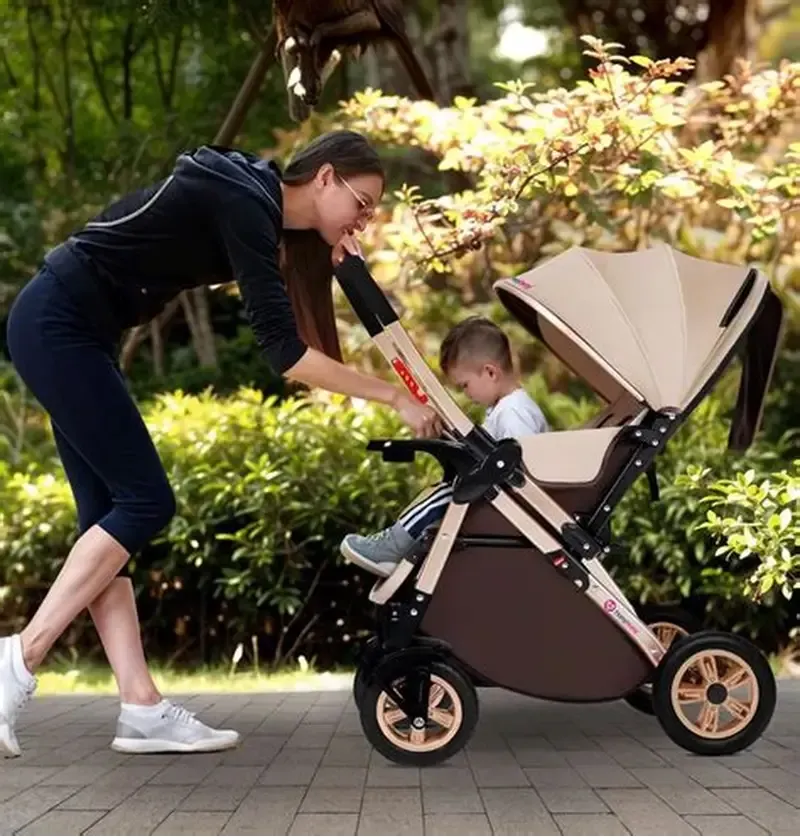 Người mẹ đang đẩy xe đẩy 2 chiều, tươi cười trò chuyện với bé sơ sinh đang nằm đối diện mình