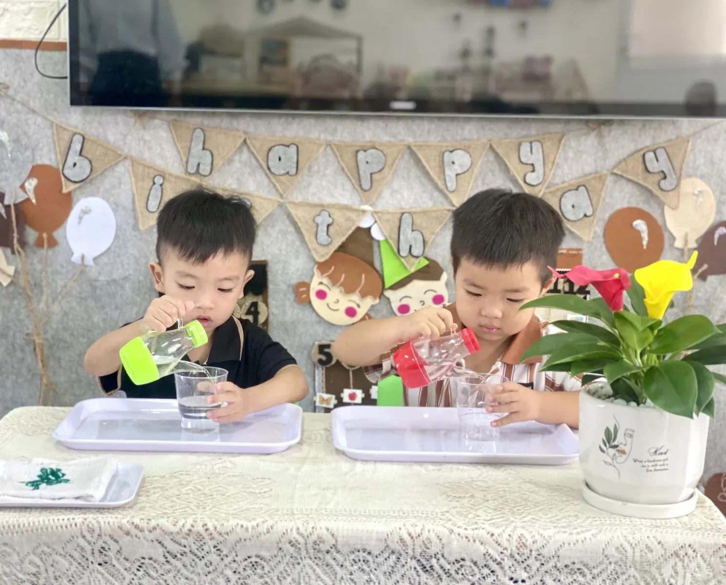 Một em bé 4 tuổi đang tự tay rót nước từ bình vào cốc